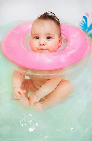 Baby swimming in bath with neck swim ring
