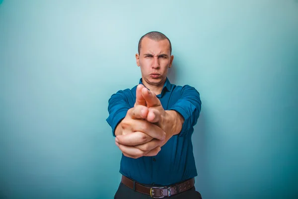 A man in a blue shirt European appearance shows hands a gun on a