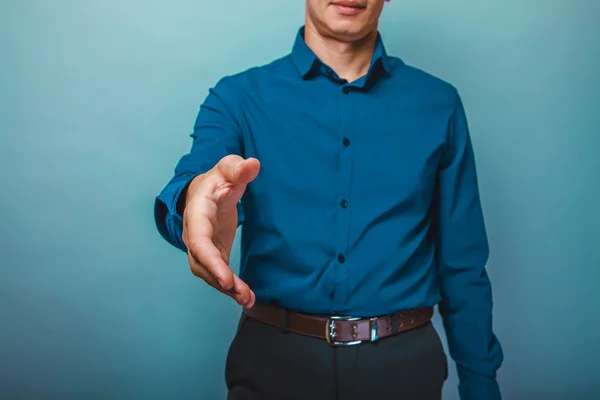 A man in a blue shirt stretches out his hand for a handshake on