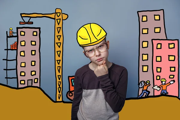 Adolescent boy deep in thought builder in a helmet of the house