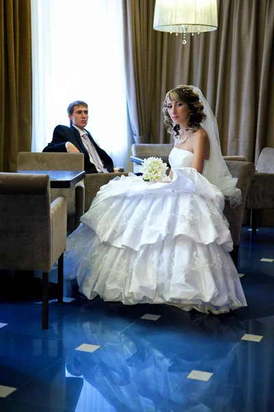 Beautiful bride and the groom sit at a table in the hotel bar