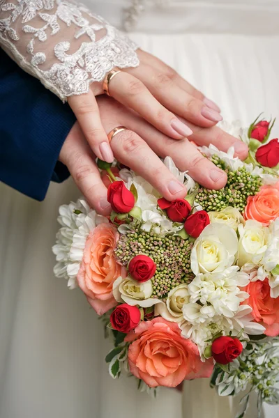 Hands and rings on wedding bouquet