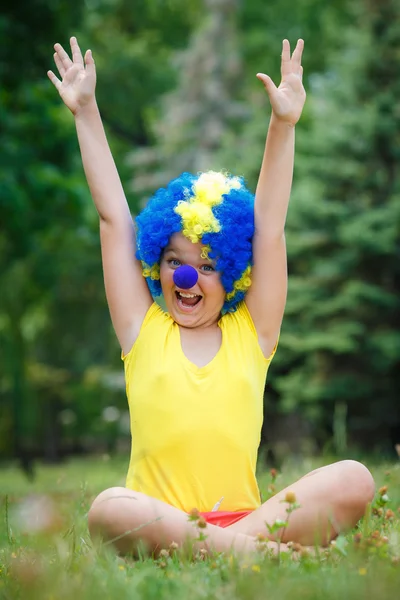 Child kid girl with party clown blue wig funny happy open arms expression and garlands in the park
