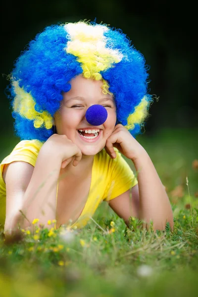 Smiling girl in clown wig with blue nose
