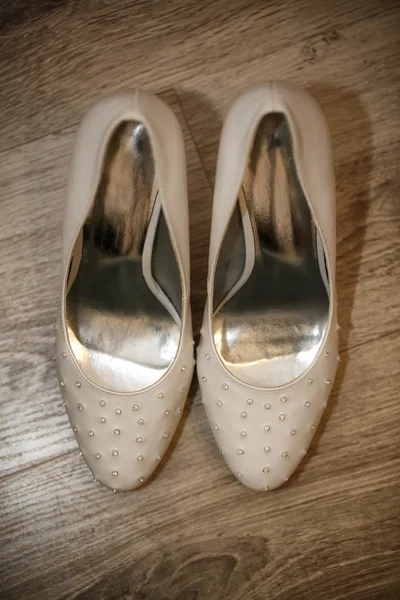 Close up of white elegant and stylish bridal shoes on the wooden floor