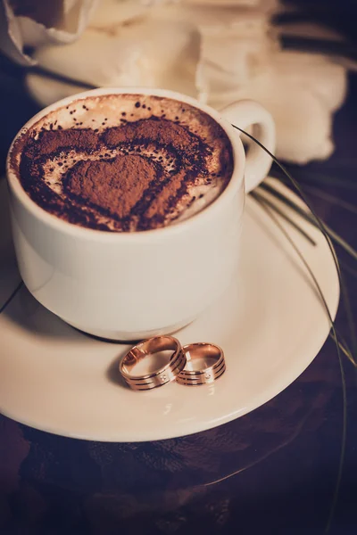 Cup of coffee, wedding rings and wedding bouquet of tulips