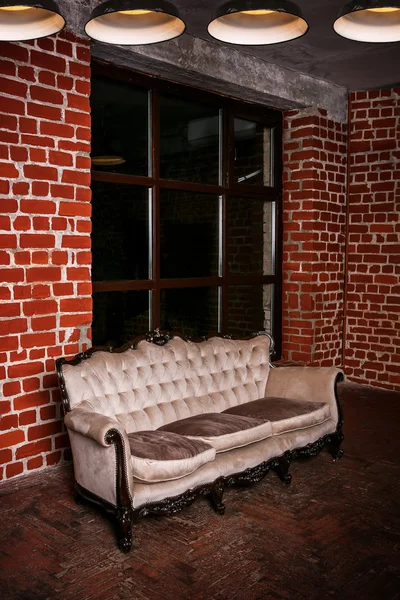 Living room with beige sofa on the  red brick wall