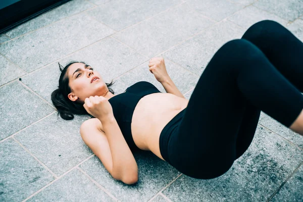 Sportive woman doing abdominal lifting legs