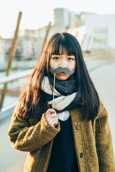 Asian hipster woman with funny fake moustache