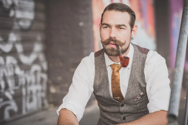 Handsome big moustache hipster man smoking pipe