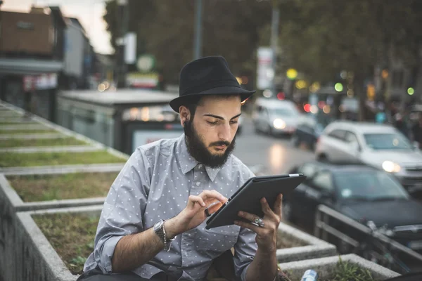 Hipster gay in hat using digital tablet