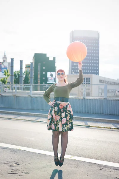 Redhead woman jumping with balloon