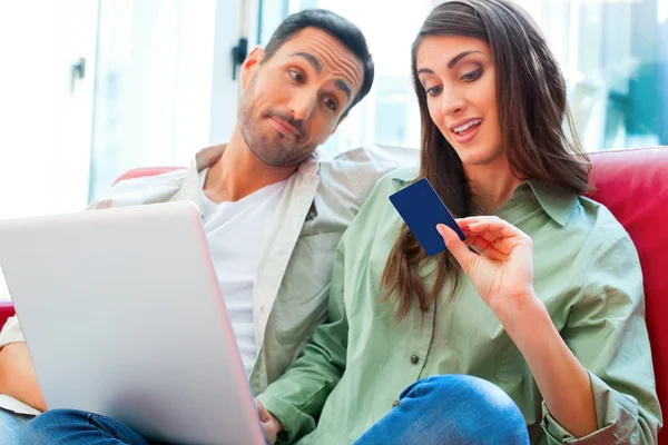 Man looking at woman with laptop and credit card
