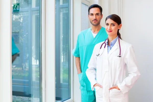 Confident female doctor standing with male surgeon