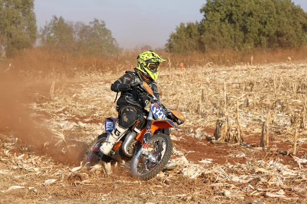Motorbike kicking up trail of dust on sand track during rally ra
