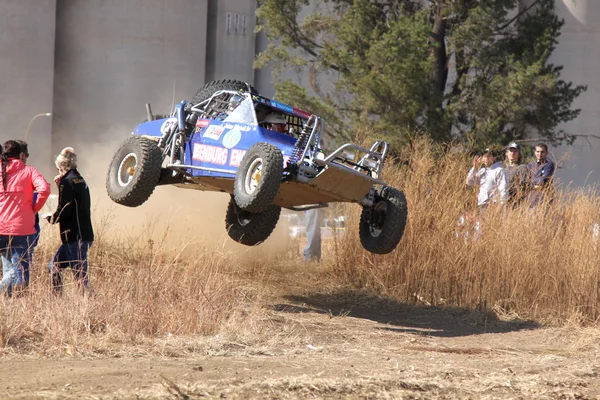 Custom twin seater rally buggy airborne over bump on sand track