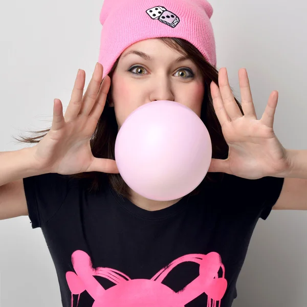 Fashion portrait of cheerful woman inflating the bubble gum in h