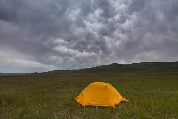 Orange tent on the background of rain clouds