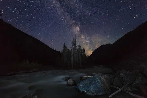 Magic night landscape with mountains, river and amazing starry s
