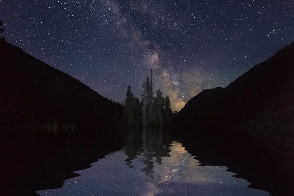 Amazing night landscape with mountains and stars. Reflection of