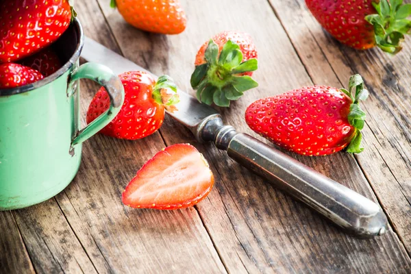 Ripe strawberries on the table next to the old knife.