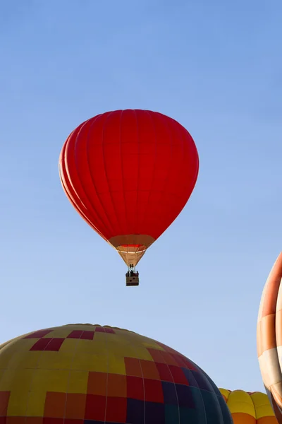 A red hot-air balloon in the sky on a beautiful summer morning.