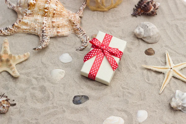 Gift box and net with shells on sand