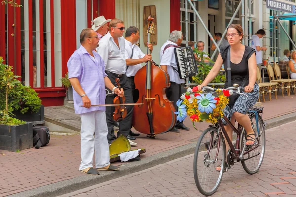 Girl cyclist with flowers and street musicians (Buskers) near ca