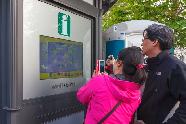 Asian tourists near interactive information scoreboard in the street of Vilnius