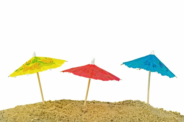 Miniature paper sun umbrellas in sand