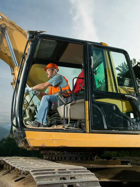 Male worker operating excavator