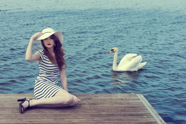 Romantic girl near a swan on lake