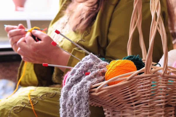 Basket with balls of yarn  and woman knitting