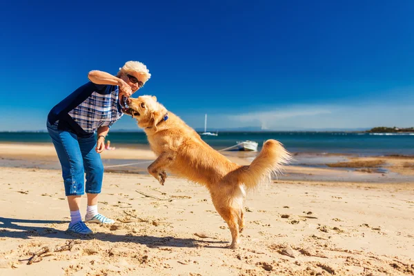 Happy woman playing on the beach with golden retriever
