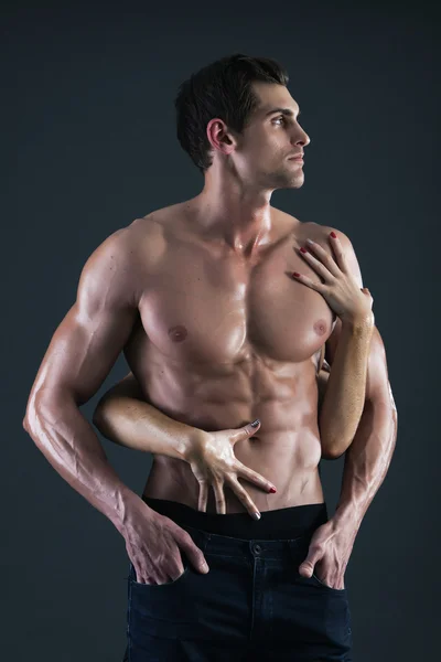 Sexy muscular man and female hands holding his chest