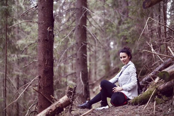 Happy young woman tourist resting on a trail in the forest