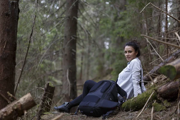 Happy young woman tourist resting on a trail in the forest