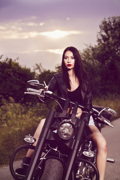 Vintage image of a beautiful woman sitting on a motorcycle and s