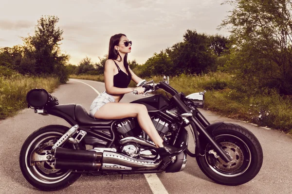 Beautiful young woman posing with a motorcycle