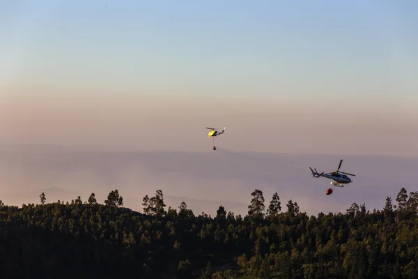 Fire-fighting helicopter with a water bucket fighting a fire on