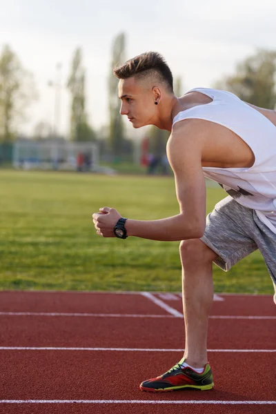 Young athlete running at the running track holding a stopwatch