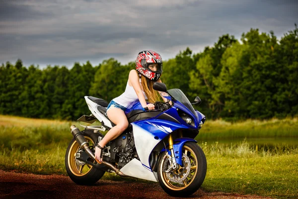 Beautiful young woman with a motorcycle speed in nature