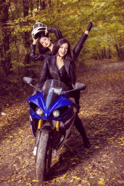 Two beautiful women passionate about motorcycles, posing in natu