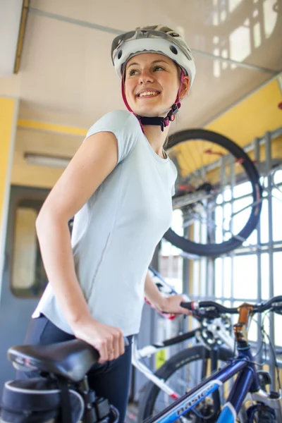 Cycling tourism: young woman traveling by train with her bike