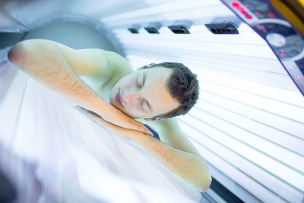 Handsome young man relaxing during a tanning session in a  solarium