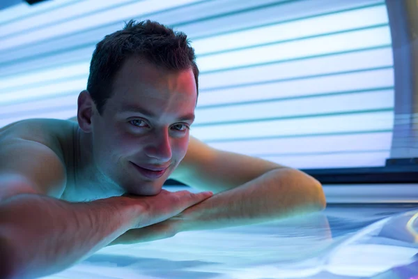 Handsome young man relaxing during a tanning session in a solarium
