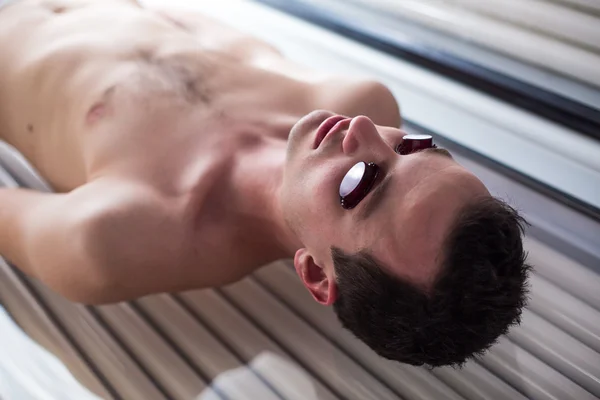 Handsome young man relaxing during a tanning session in a solarium