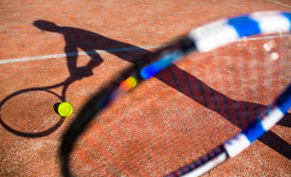 Shadow of a tennis player in action on a tennis court