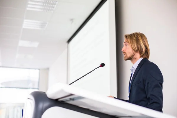 Handsome young man giving a speech at a conference