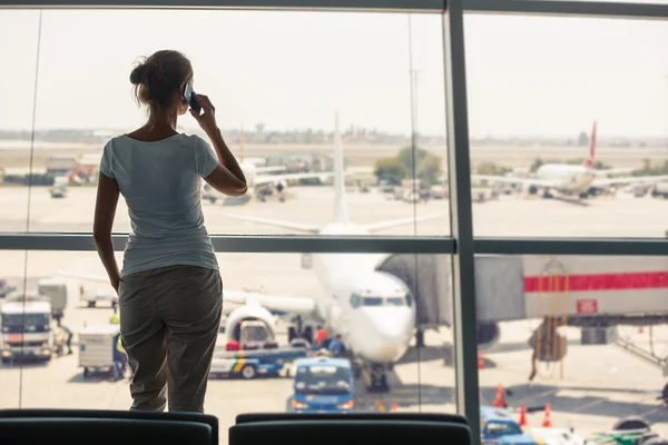 Pretty, young woman waiting at a gate area of a modern airport f